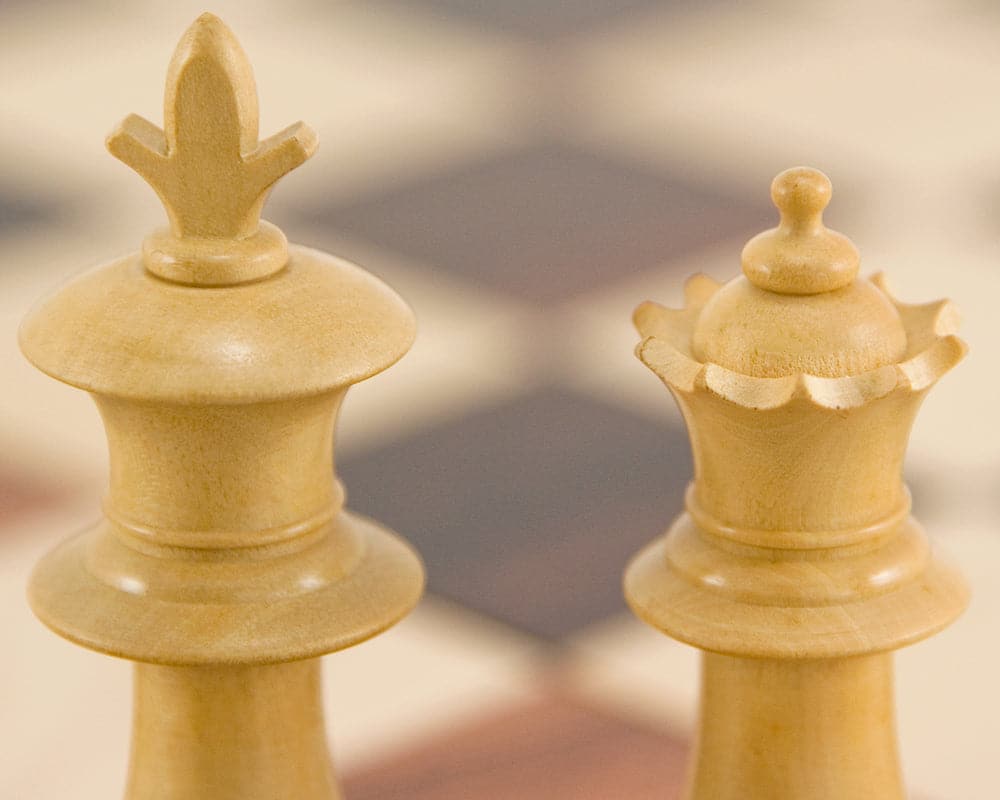 Ebonised Staunton chess pieces king and queen on chessboard background