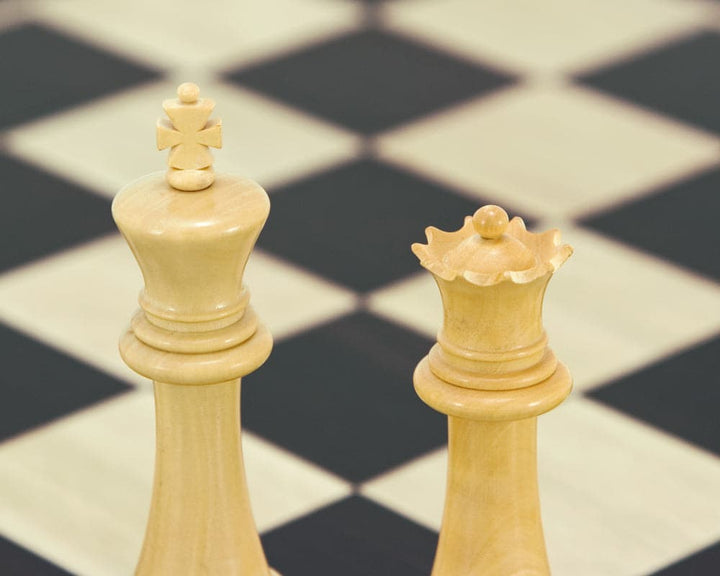 Hand crafted natural boxwood king and queen chess pieces on a chessboard.