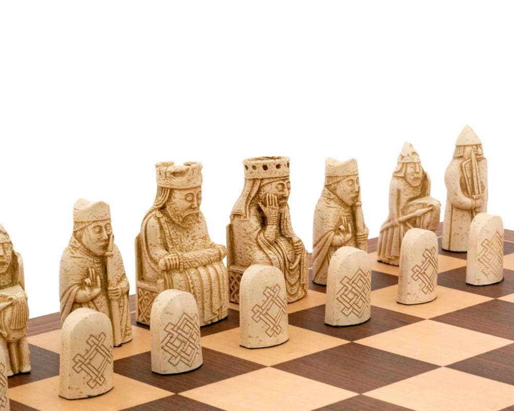 Isle of Lewis chess set on a walnut and maple chessboard featuring intricately carved pieces resembling ancient figures.